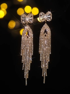 Macro shot of luxury bowknot tassel earrings with shimmering crystals on gold metal