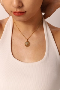 Detail of gold evil eye necklace with crescent moon and zircon inlay worn by a model