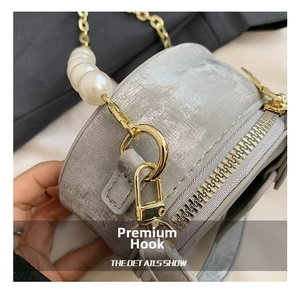 Détail du crochet doré et de la chaîne en perles sur un mini sac rond gris