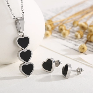 Detail view of heart shell necklace and stud earrings set in silver and black metal