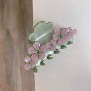 Detail of light green acetate hair claw clip featuring pink flowers and green rhinestones