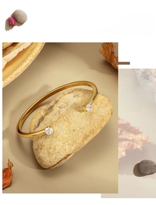 Detailed view of an 18K gold plated open cuff bracelet with two sparkling cubic zirconia