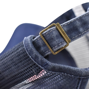 Dettaglio della fibbia in metallo e denim blu lavato su un cappello a rete con coda di cavallo