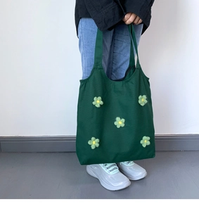 Detailed close-up of dark green canvas tote bag featuring handmade yarn flower accents