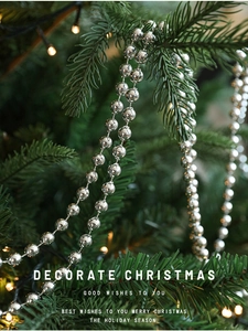 Close-up of silver beaded garland hanging on a Christmas tree with festive warm lighting
