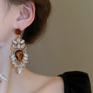 On-ear detail of vintage gold drop earrings with amber stones and colorful crystals