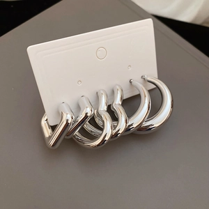 Détail de l'ensemble de boucles d'oreilles créoles argentées en formes variées sur carte