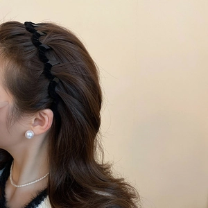 Close-up of velvet braided headband with large pearl earrings on a female model