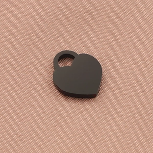 Detailed view of a black heart-shaped pendant with a silver loop on pink textured fabric