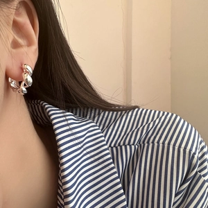 Elegant silver twisted spiral hoop earrings worn by a model in a natural setting