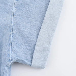 Detailed close-up of folded denim cuffs showing precise stitching and light blue wash texture