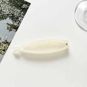 Close-up of cream plastic banana hair clip with secure metal rivet and comb teeth