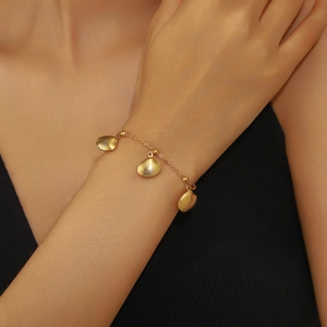 Close-up of a gold shell charm bracelet featuring delicate seashell pendants and beads