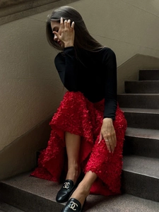 Detail of red petal textured midi skirt with black leather loafers featuring gold buckle