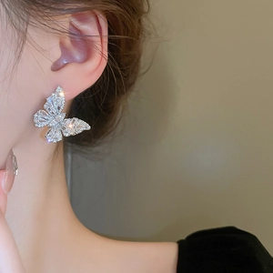 Macro detail of silver butterfly earrings featuring sparkling cubic zirconia on model