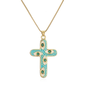 Detail of 18K gold-plated cross necklace featuring blue enamel eye patterns and green gemstone