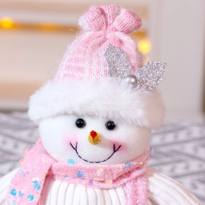 Close-up of a pink sequined scarf and knitted hat on a plush snowman Christmas ornament
