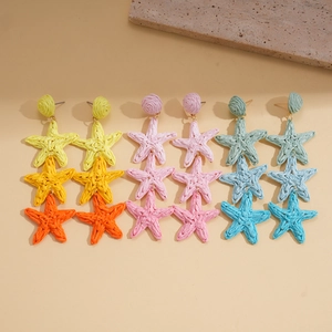 Detailed view of handmade raffia star tassel earrings in colorful woven patterns