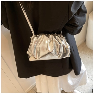 Detail of silver metallic dumpling bag featuring pleated texture and slim shoulder strap