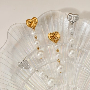 Elegant heart-shaped pearl fringe earrings in gold and silver finish on shell tray