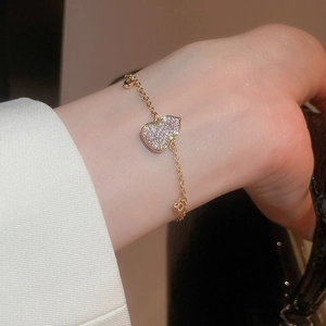 Close-up of 18k gold plated bracelet with sparkling heart charm on female wrist