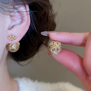Macro detail of a hollow gold heart earring with fine rhinestones and pearl-style closure