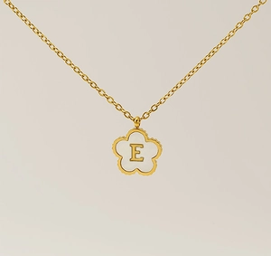 Macro shot of 18K gold clover pendant featuring white shell inlay and letter E detail