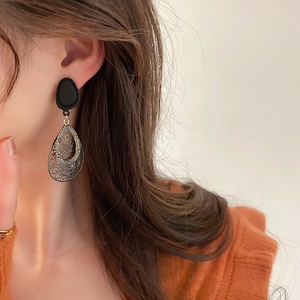 Retro black teardrop earrings with rhinestones and hollow floral patterns on a model