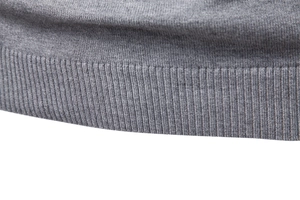 Close-up of gray knit sweater showing high-quality ribbed hem and fine fabric texture