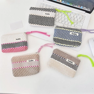 Detail of colorful striped woven makeup pouches with zipper and handle on a desk