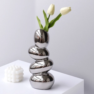 Silver pebble-shaped irregular vase with mirror finish and white tulips for home decor