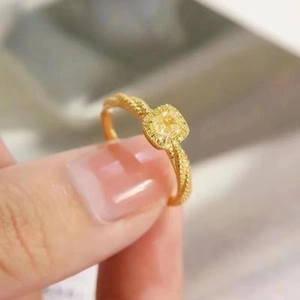 Macro shot of gold twist band ring with yellow cushion-cut zircon and pavé halo