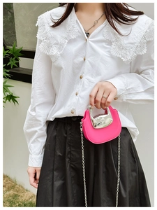 Pink mini crossbody bag with a silver metal handle shown in a professional model shot