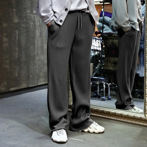Detail showing the deep gray pleated texture and fluid drape of wide-leg casual pants