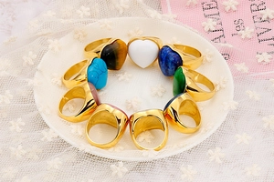 Collection of gold heart rings with colorful gemstones on a white lace background