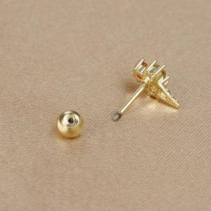 Macro detail of 18K gold plated screw-back earring with orange gemstone and threaded post