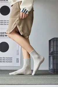 Close-up of light grey ribbed knit cotton socks worn with khaki shorts in a studio setting