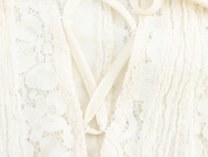 Detailed macro view of ivory lace fabric and satin criss-cross tie-up design on dress