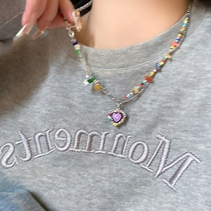 Close-up of multicolor beaded necklace with purple heart pendant on model