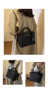Detailed view of black nylon tote bag with polished leather handles and adjustable strap