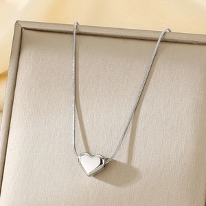 Vue macro d'un pendentif cœur argenté sur une chaîne serpent sur un coffret