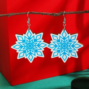 Detailed shot of Christmas snowflake drop earrings hanging on a natural wooden branch