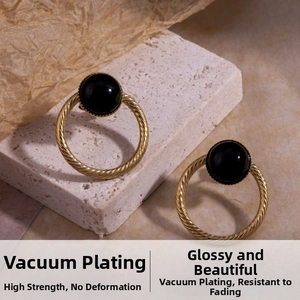 Close-up of vintage C-shaped gold heart earrings with black onyx on stone base
