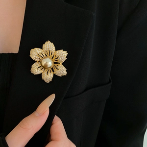 Detail of gold flower brooch with large pearl and zircon on black suit lapel