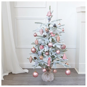Detail of pink ornaments and glitter balls on a white flocked artificial Christmas tree
