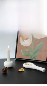 Minimalist matte white ceramic candle holders set on a table with warm floral decor