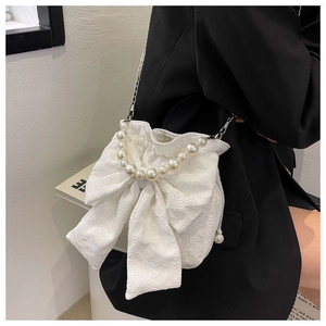 Detail of white bow handbag with pearl handle and jacquard fabric on black blazer