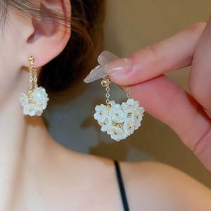 Elegante weiße Blumen-Ohrringe mit Goldkette am Model, modischer Damenschmuck
