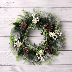Couronne de Noël avec feuilles vertes, pommes de pin et baies blanches sur bois vintage