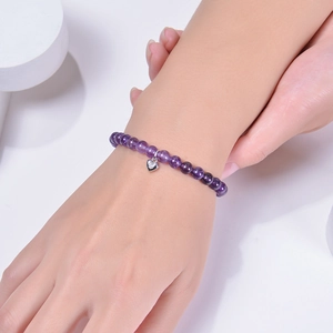 6mm natural amethyst beaded bracelet with silver heart pendant worn on a wrist
